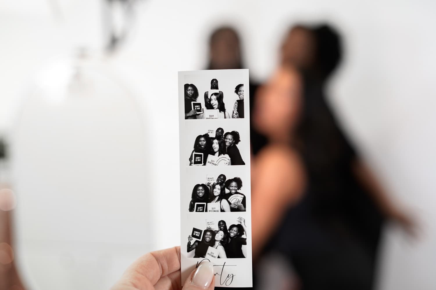 Black and white photo booth film strip being held up at a wedding